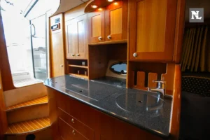 Interior del Windy 32 Scirocco, vista de la cocina con encimera, fregadero, armarios y escalera.