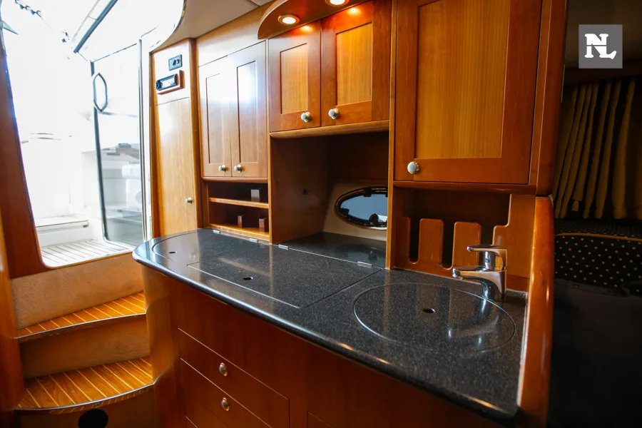 Interior del Windy 32 Scirocco, vista de la cocina con encimera, fregadero, armarios y escalera.