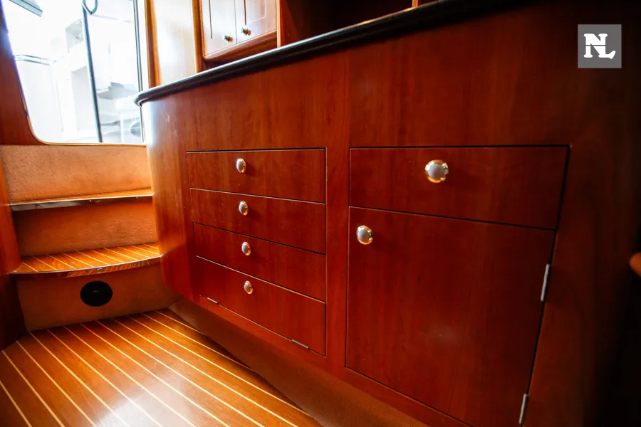 Interior de Windy 32 Scirocco, vista de armarios de madera, cajones y escalera junto al suelo de teca.