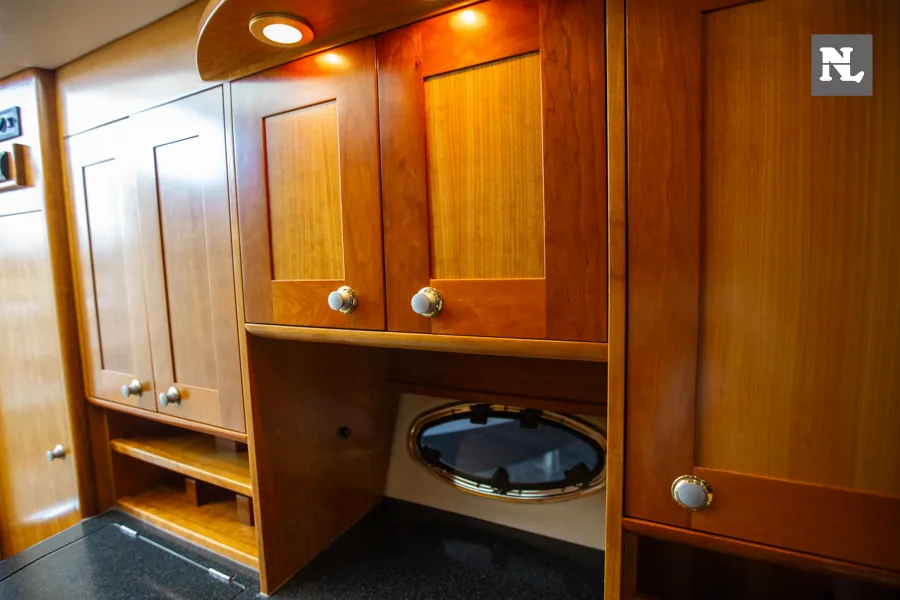 Interior del Windy 32 Scirocco, vista de armarios de madera, estantes y portillo ovalado.