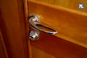 Interior del Windy 32 Scirocco: primer plano de manilla cromada en una puerta de madera.