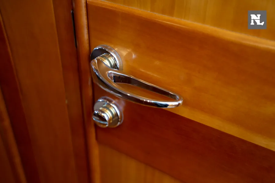 Interior del Windy 32 Scirocco: primer plano de manilla cromada en una puerta de madera.