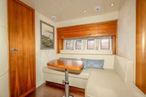 Innenraum der gebrauchten Windy 46 Chinook mit L-förmigem Sofa und zentralem Tisch – Nautic Luis Empuriabrava