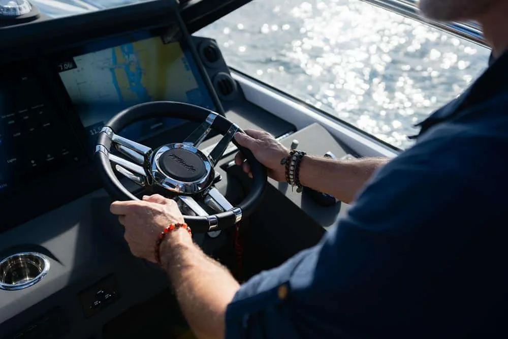 Windy Camira 40 RS, interior helm station with steering wheel, navigation screen and pilot's hands.