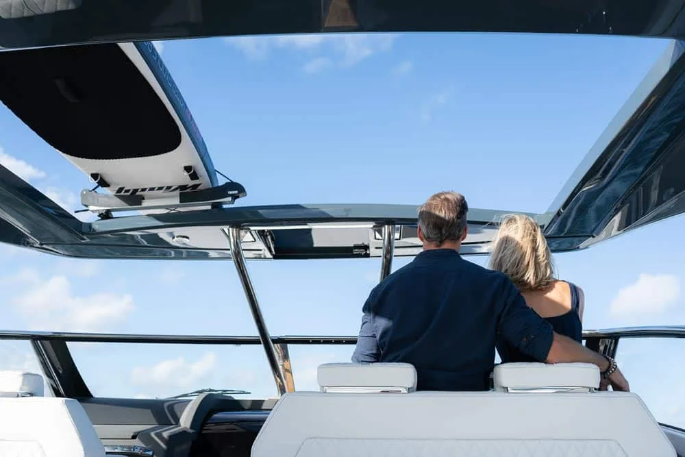 Windy Camira 40 RS, aft view of the exterior helm station with two people seated and a panoramic windshield.