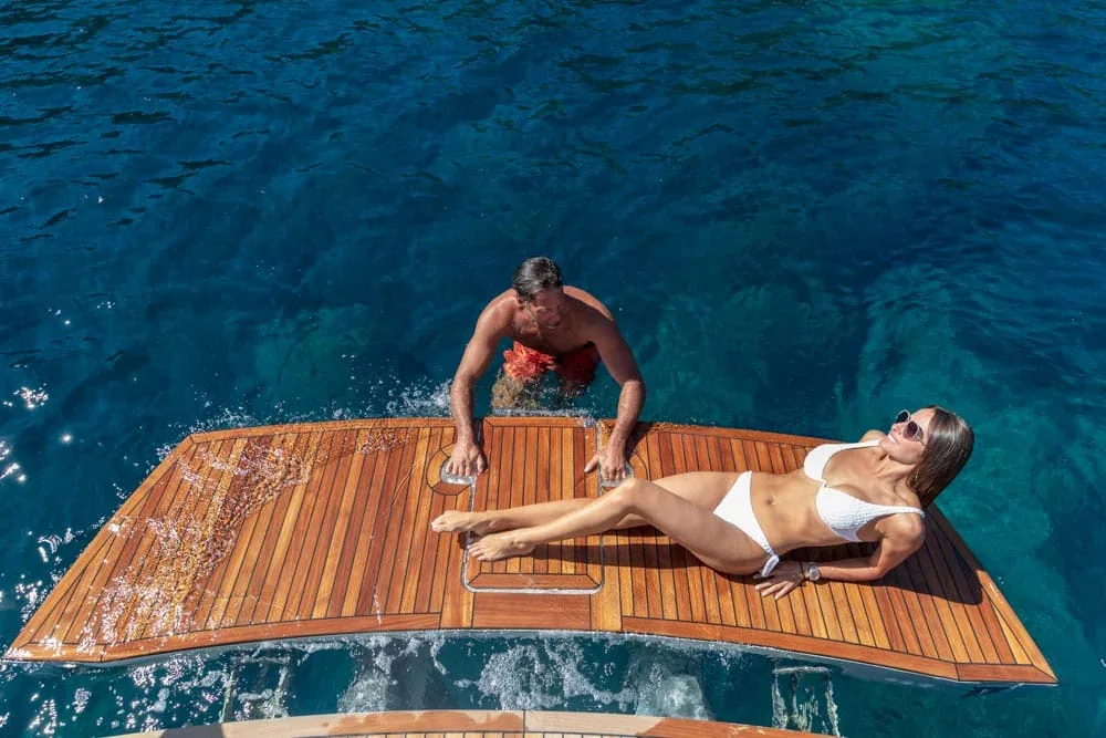 Windy Camira 40 RS: top view of the teak bathing platform with two people over the sea.