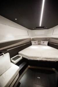 Cama doble del camarote de proa con uno de los dos asientos laterales