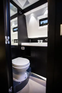 Baño de la Windy SR44 Blackhawk de segunda mano en Nautic Luis, Empuriabrava, con lavabo, espejo y acabados de lujo en madera y acero inoxidable.