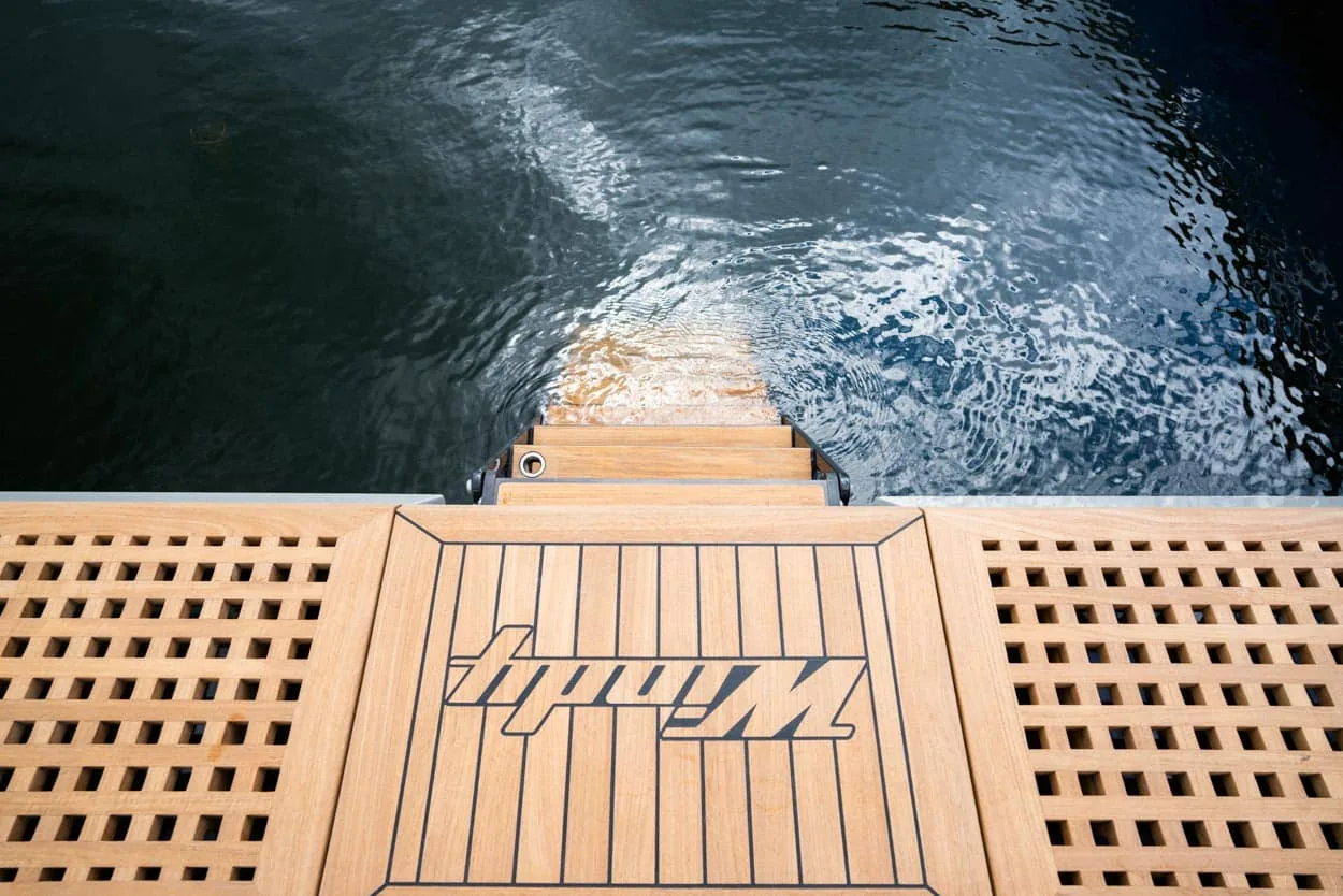 Top view of the teak swim platform of the Windy SR52 Blackbird, with a central logo and water in the background