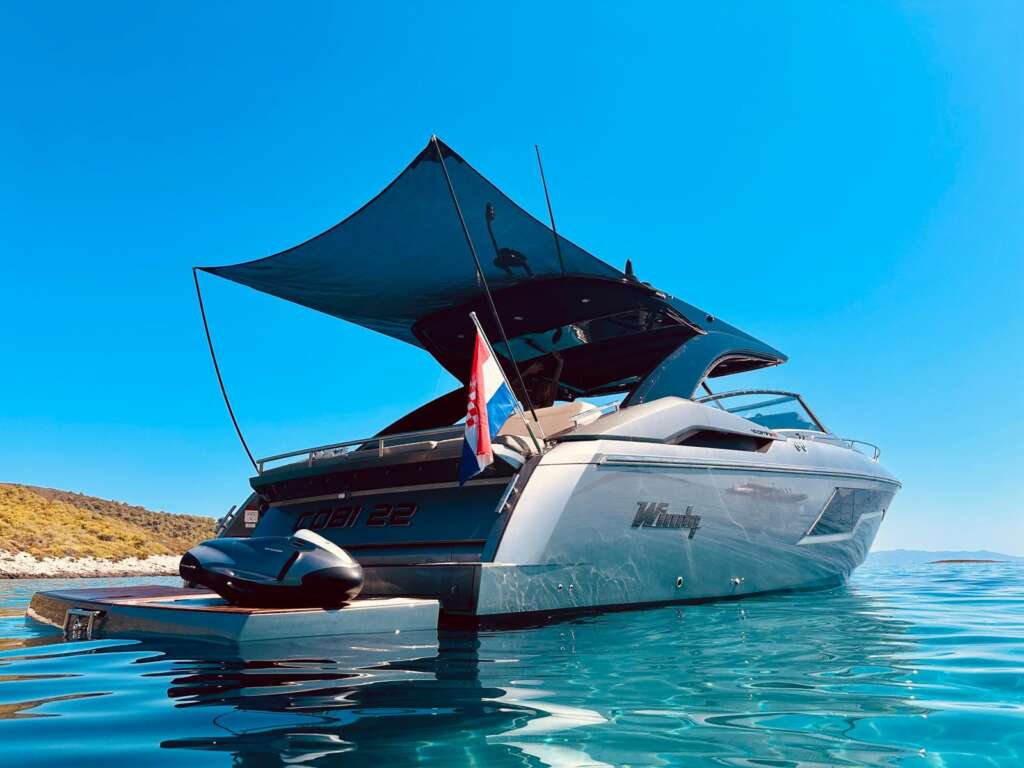 Windy 40 Camira RS visto de popa y estribor, fondeado; toldo, plataforma y embarcación auxiliar visibles.